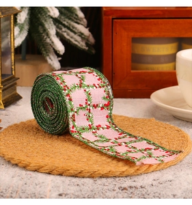 Pink Christmas ribbon with floral pattern displayed on a rustic holiday setting background