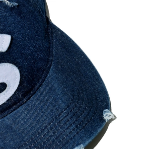 Detailansicht der Jeans-Baseballkappe mit abgenutzten Kanten und S-Buchstaben-Filz