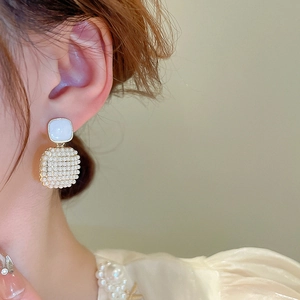 Detail of square pearl earrings featuring faux pearl inlay and elegant gold accents