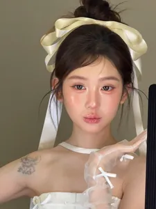 Detailed view of oversized off-white satin bow hair clip with matching sheer tulle gloves