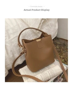 Detail view of tan bucket bag with MAGGIE logo, metal buckle and adjustable strap