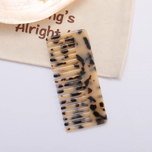 Macro detail of wide-tooth tortoiseshell acetate hair comb on a canvas bag