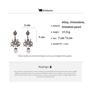Detail view of vintage bow earrings with rhinestones and white imitation pearl drop