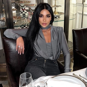 Detailed close-up of grey long-sleeve bodysuit with pleated V-neck design