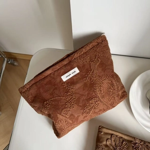 Detail of camel faux suede makeup bag with floral embroidery and simple wish label