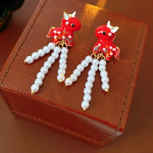 Detailed macro view of vintage red enamel pony earrings with elegant pearl tassels