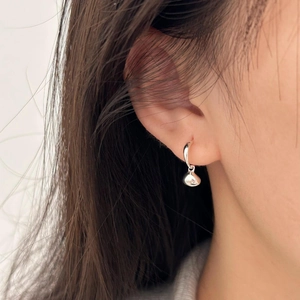 Macro shot of minimalist 925 sterling silver hoop earrings with polished drop charms