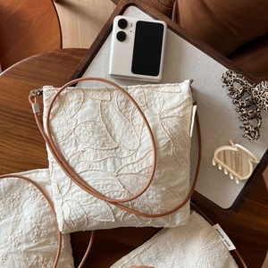Detail of leaf embroidery on minimalist beige linen crossbody bag with a leather strap