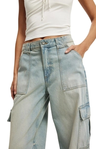 Close-up of light blue cargo jeans showing front pockets and denim texture on model