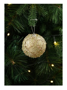 Close-up of golden glitter Christmas ball with sequins on a lit Christmas tree