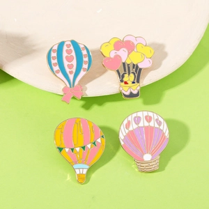 Detailed view of four colorful hot air balloon enamel pins on a natural wooden tray