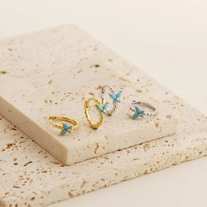 Detailed view of s925 silver butterfly earrings in gold and silver finish with blue accents