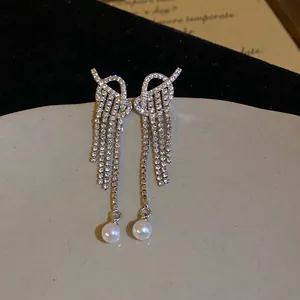 Elegant silver knot earrings featuring crystal tassels and round white pearls in 45-degree view