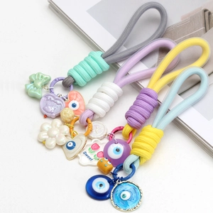 Détail de porte-clés tressés colorés avec œil maléfique et breloques Sweet en résine