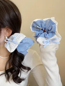 Detail of blue plaid hair scrunchie with lace trim, bowknot and pearl decoration