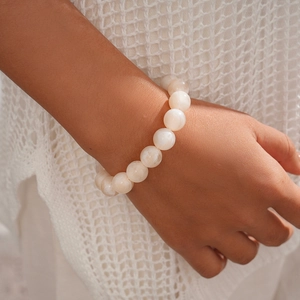 Detail of elegant white acrylic beaded bracelet with smooth glossy finish on knit fabric