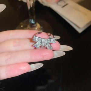 Close-up of a silver bow ring with zircon pavé setting on a finger, elegant detail