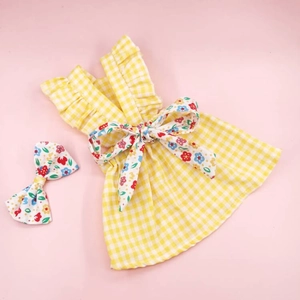 Detalle del vestido para perro de cuadros amarillos con lazo floral y accesorio para el pelo
