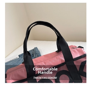 Detail view of comfortable wide black carry handles on a pink fitness travel bag