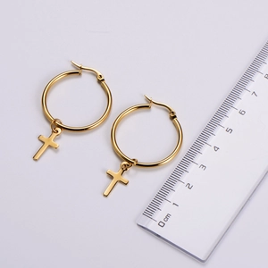 Détail de boucles d'oreilles créoles dorées avec pendentif croix, mesure de 2 à 3 cm