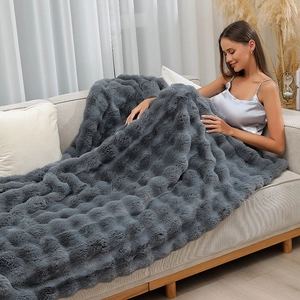 Close-up of thick dark grey faux fur blanket with bubble texture on a modern sofa