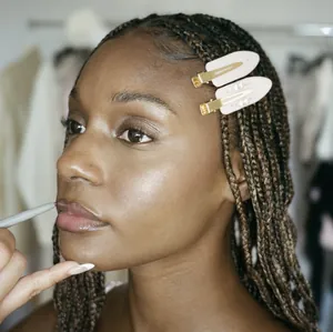 Detail showing two floral rhinestone hair clips on a model with braided hair