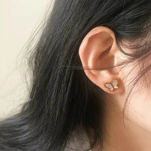 Detail view of butterfly stud earrings featuring white shell inlay and gold plating