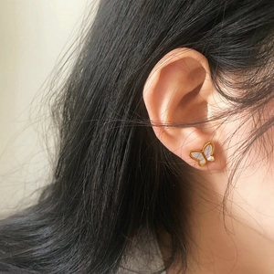 Detail view of butterfly stud earrings featuring white shell inlay and gold plating