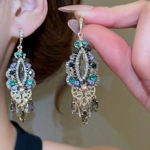 Detail of vintage chandelier earrings with multi-colored crystals and gold hollow metalwork