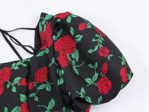 Détail d'une robe à manches bouffantes noire avec jacquard de roses rouges et fines bretelles