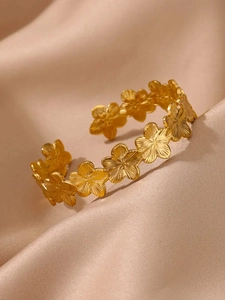 Détail d'un bracelet fleuri doré 18K avec texture brossée sur fond en satin chic