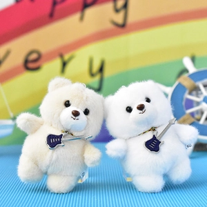 Close-up of two adorable white and cream plush bear keychains with guitar pendants
