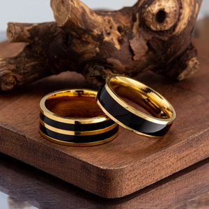 Detail view of gold and black enamel titanium rings on a rustic dark wood surface