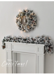 Detail of pre-lit flocked Christmas wreath and garland set with pinecones and bells
