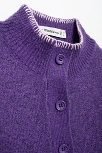 Dettaglio del colletto in maglia viola con cuciture rosa e trama in lana