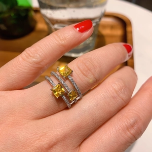 Close-up of triple-layered silver ring featuring three square yellow gemstones and pavé accents