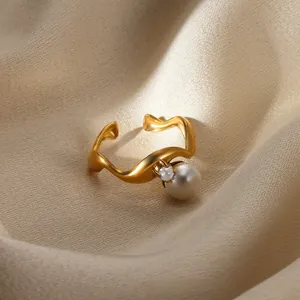 Detailed view of wave-shaped golden open ring with white pearl and zircon on silk fabric