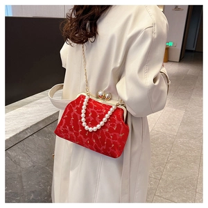 Close-up of red velvet shell bag with pearl handle and ornate golden floral patterns