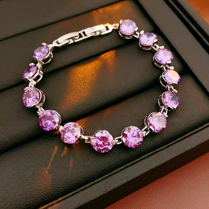 Macro shot of purple round zircon bracelet with silver clasp in a textured gift box