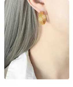 Detailed close-up of gold woven mesh hoop earrings on a model showing honeycomb texture