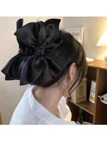 Close-up of a large black satin bow hair claw clip styled on a woman's hair