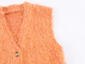 Detail of soft orange plush knit vest showing fuzzy texture and tortoiseshell button