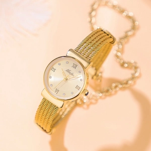 Detail of gold woven mesh strap watch with Roman numerals and rhinestone accents on pink background
