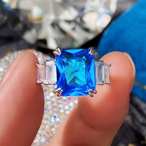 Macro shot of rectangular blue zircon ring featuring step-cut side stones on silver band