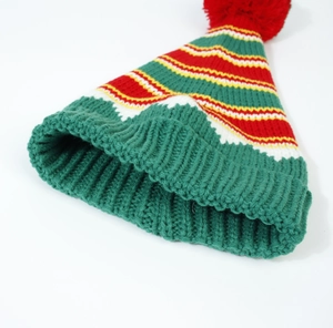 Detailed close-up of chunky knit Christmas hat with colorful stripes and red pompom