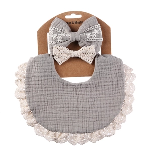 Three-piece baby set with grey cotton muslin bib and matching lace bow headbands
