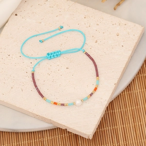 Bohemian handmade beaded bracelet with pearl on a natural stone and bamboo mat background