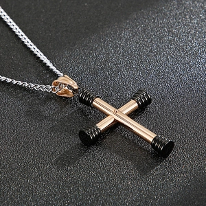 Detailed view of a rose gold dumbbell cross pendant on a silver twist chain necklace