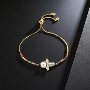 Macro shot of Hamsa hand and evil eye charm on adjustable gold zircon bracelet
