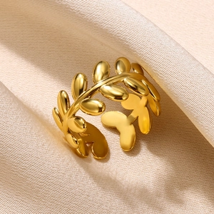 Macro shot of an adjustable golden laurel leaf ring on elegant champagne silk fabric